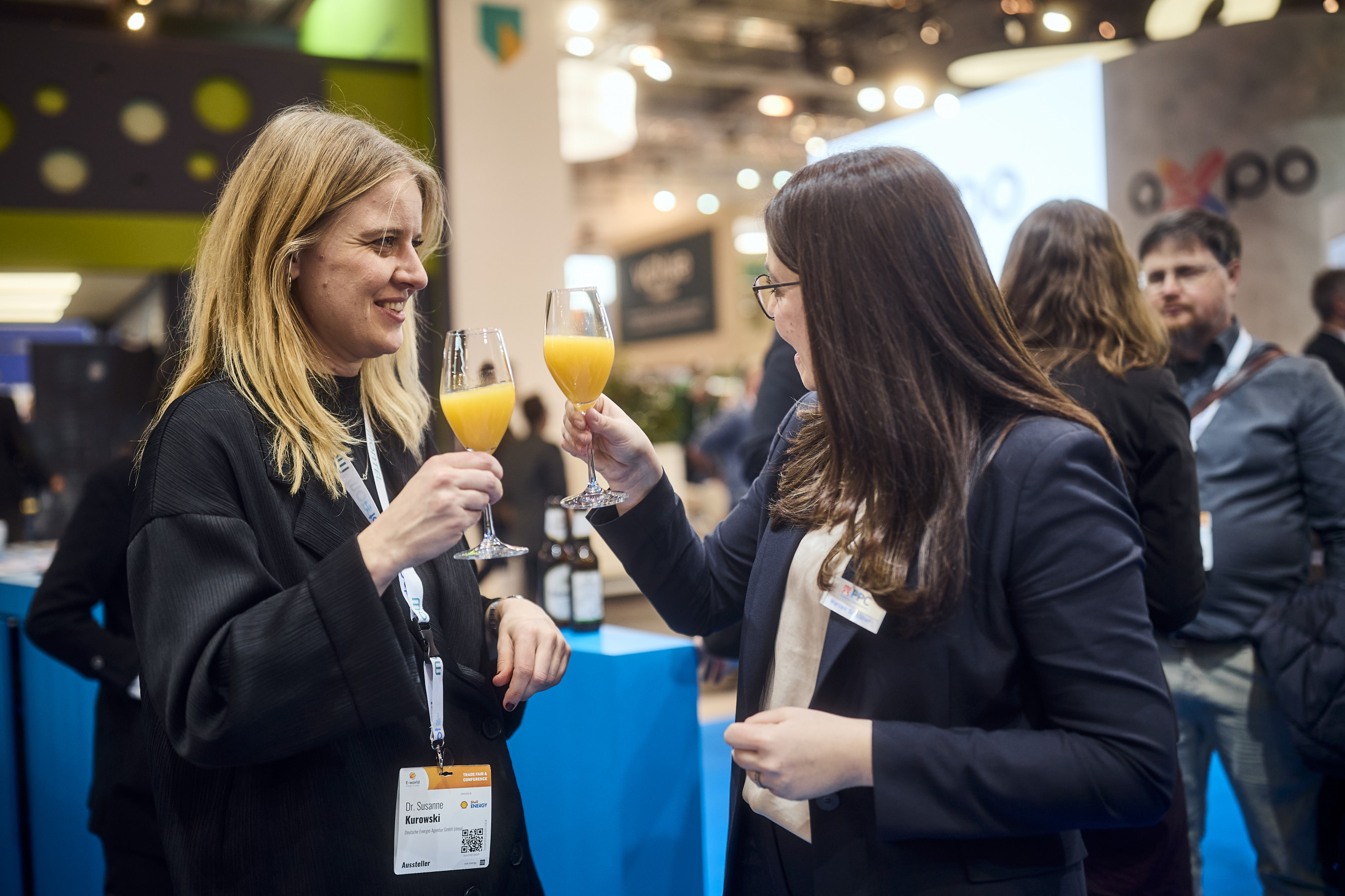 Zwei Frauen stoßen an auf der PPC-Stand der E-World 2025